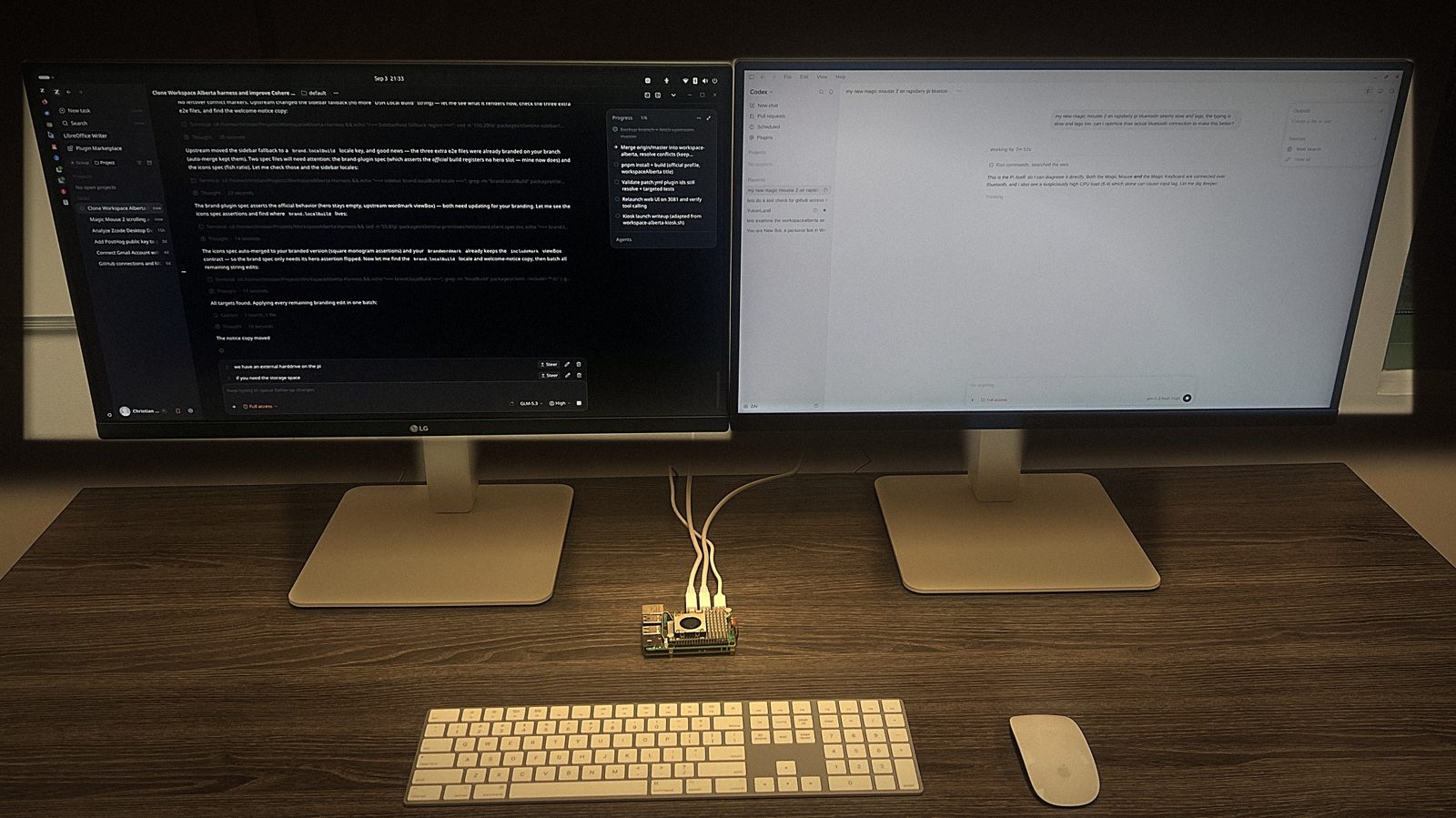 A working AI Terminal on a desk: a small Raspberry Pi computer with a cooling fan, cabled to two displays. The left display shows an agent working through a code merge with a progress checklist; the right shows a chat session.